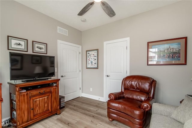 living area with light wood-style flooring, a ceiling fan, and baseboards