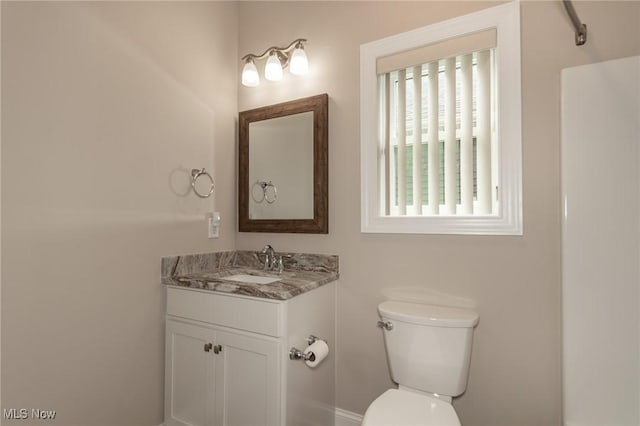bathroom with toilet, vanity, and baseboards