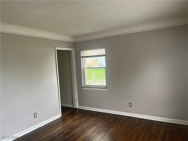 empty room featuring baseboards and dark wood finished floors