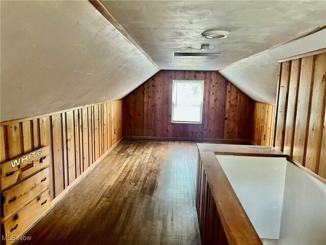 bonus room with hardwood / wood-style flooring, vaulted ceiling, and wood walls