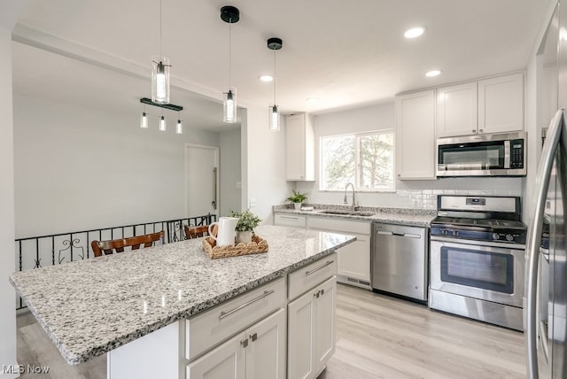 kitchen featuring stainless steel appliances, a sink, light wood-type flooring, white cabinetry, and recessed lighting