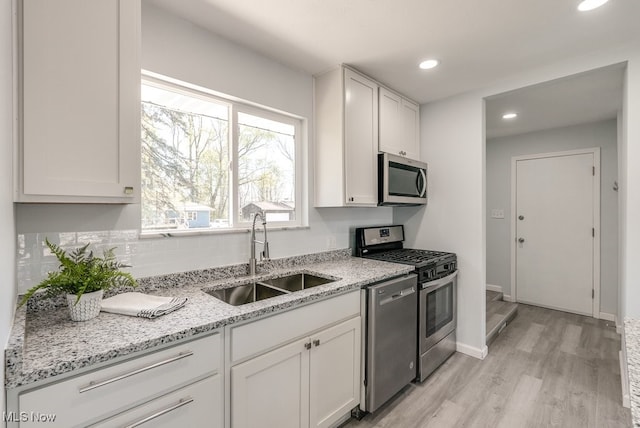 kitchen featuring stainless steel appliances, a sink, light wood-type flooring, white cabinetry, and recessed lighting