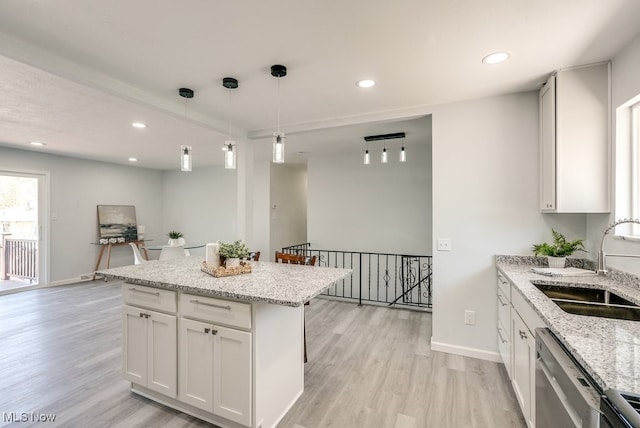 kitchen featuring a sink, dishwasher, light wood-style flooring, baseboards, and recessed lighting