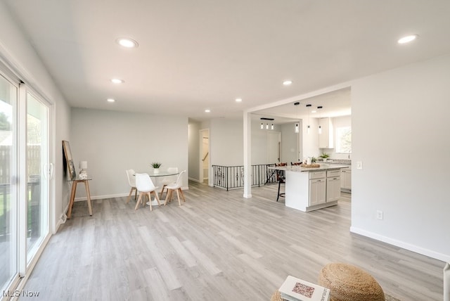 living area featuring recessed lighting, light wood-style floors, baseboards, and stairs