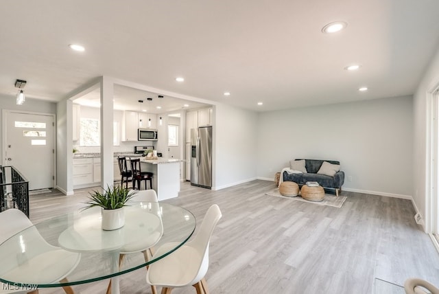 dining room with light wood-style floors, recessed lighting, and baseboards
