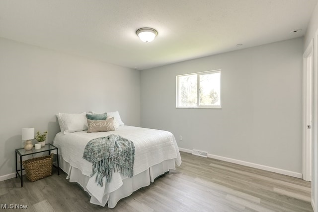 bedroom with light wood finished floors and baseboards
