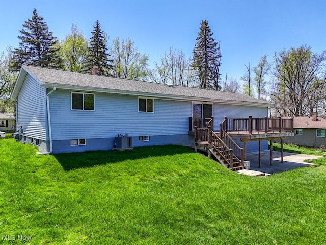 rear view of house featuring a deck, a patio, a lawn, a chimney, and central AC