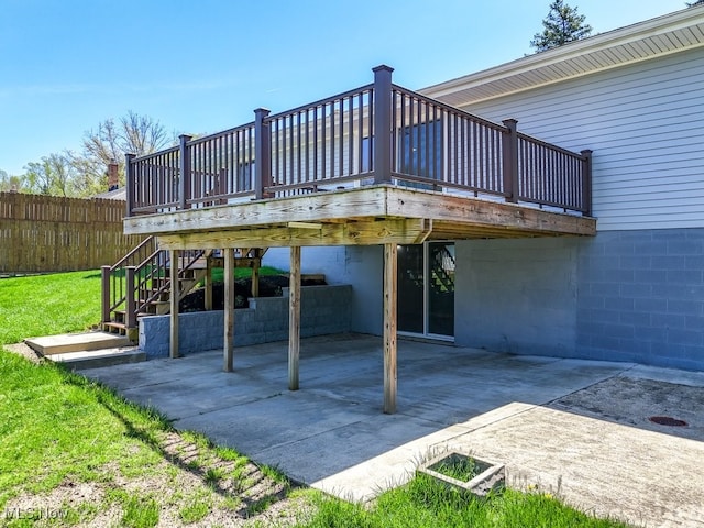 view of patio featuring a deck, fence, driveway, and stairway