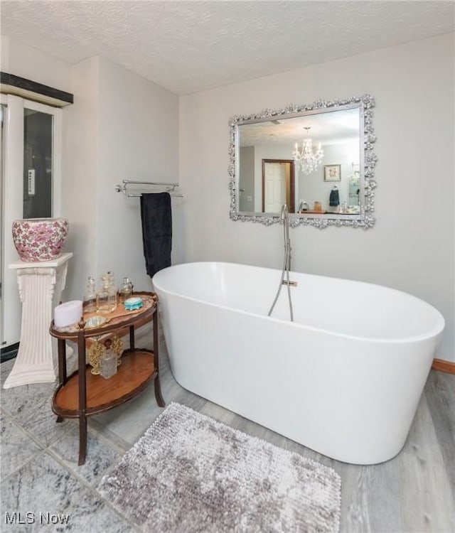 3286 Marks Rd, Medina, OH 44256 - full bathroom featuring a freestanding tub, wood finished floors, a textured ceiling, baseboards, and a chandelier