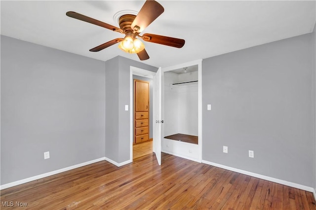 unfurnished bedroom with baseboards, wood finished floors, a ceiling fan, and a closet