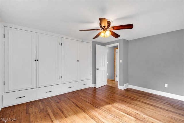 unfurnished bedroom with baseboards, two closets, light wood-type flooring, and ceiling fan