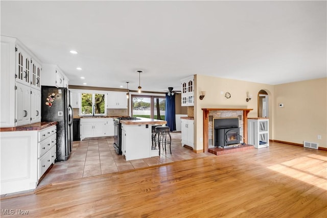 kitchen featuring black appliances, a breakfast bar area, white cabinetry, light wood-style floors, and recessed lighting