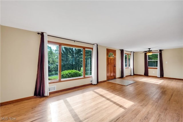 unfurnished living room with light wood-style flooring, baseboards, and ceiling fan