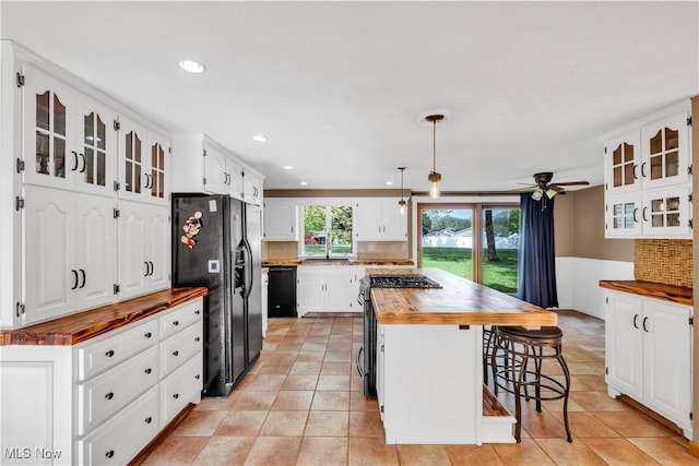 kitchen featuring black appliances, wood counters, a kitchen breakfast bar, decorative backsplash, and recessed lighting