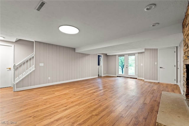 unfurnished living room featuring light wood finished floors, stairs, and baseboards