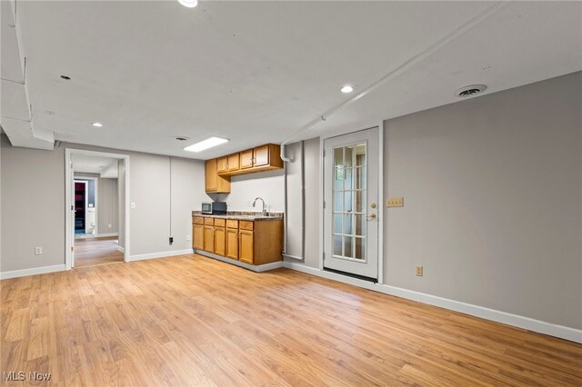 kitchen with light wood-type flooring, a sink, baseboards, recessed lighting, and brown cabinetry