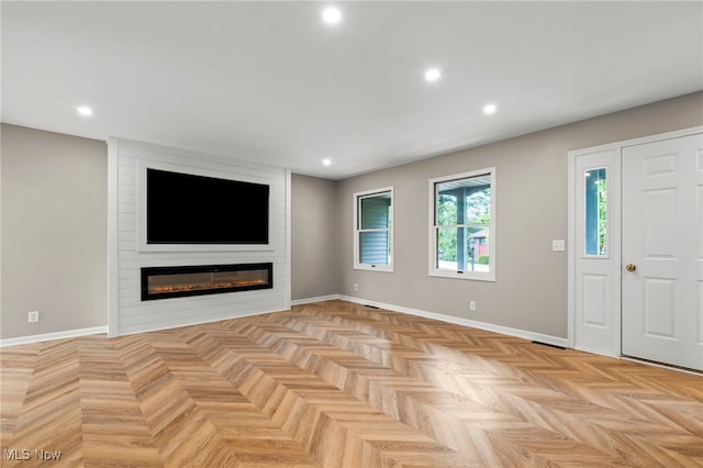 unfurnished living room featuring a large fireplace, baseboards, and recessed lighting