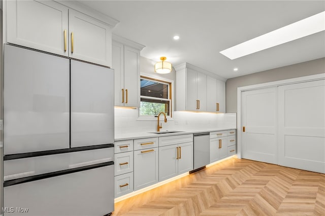kitchen with a sink, stainless steel appliances, a skylight, light countertops, and backsplash