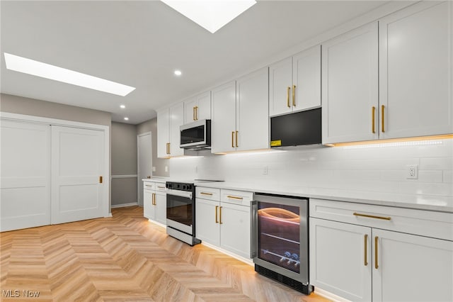 kitchen with beverage cooler, electric range, recessed lighting, stainless steel microwave, and a skylight