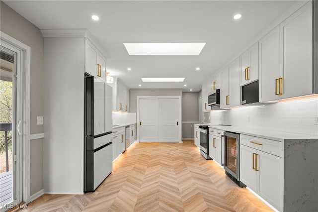 kitchen featuring stainless steel appliances, wine cooler, a skylight, light countertops, and recessed lighting