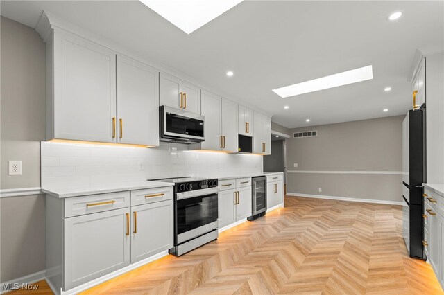 kitchen featuring electric range oven, wine cooler, a skylight, freestanding refrigerator, and tasteful backsplash