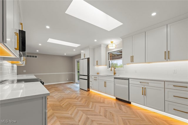 kitchen with dishwasher, a skylight, freestanding refrigerator, a sink, and recessed lighting