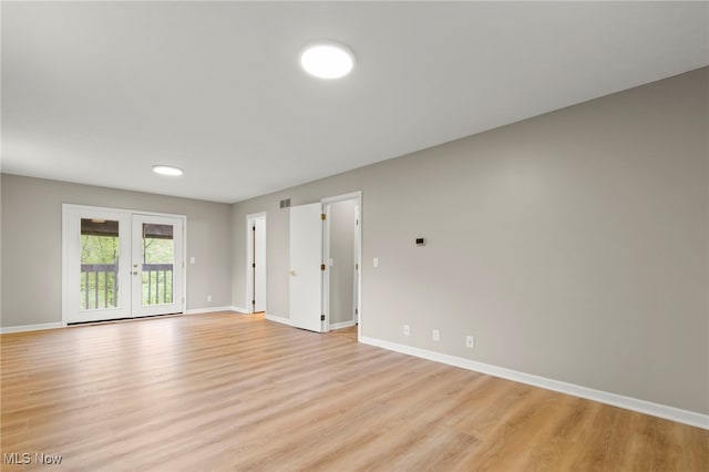 empty room featuring light wood-type flooring, baseboards, and french doors