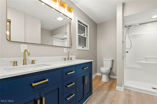 bathroom featuring wood finished floors, a shower, a textured ceiling, toilet, and baseboards