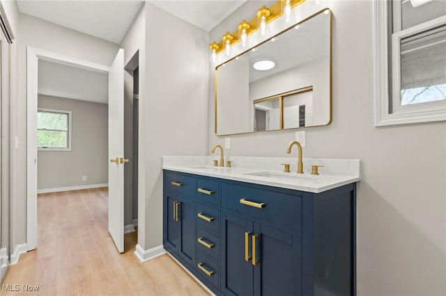 full bathroom featuring wood finished floors, double vanity, and baseboards