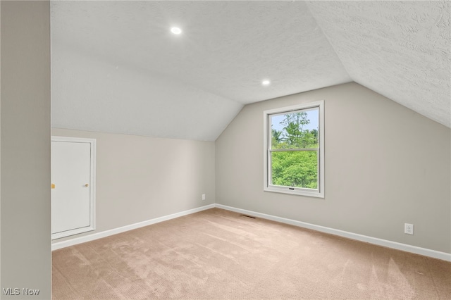 additional living space featuring baseboards, carpet floors, lofted ceiling, a textured ceiling, and recessed lighting