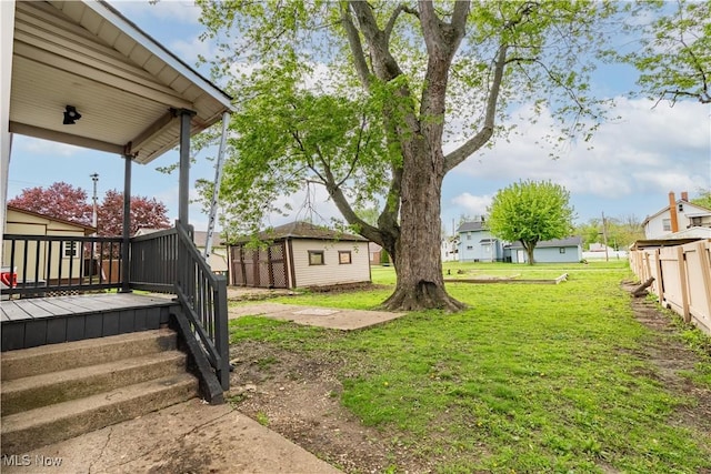 view of grassy yard featuring an outbuilding and a deck