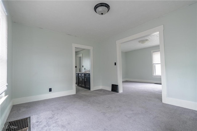 unfurnished living room featuring carpet flooring and baseboards