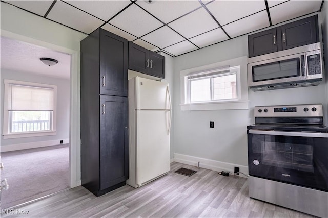 kitchen featuring appliances with stainless steel finishes, baseboards, plenty of natural light, light wood finished floors, and a paneled ceiling