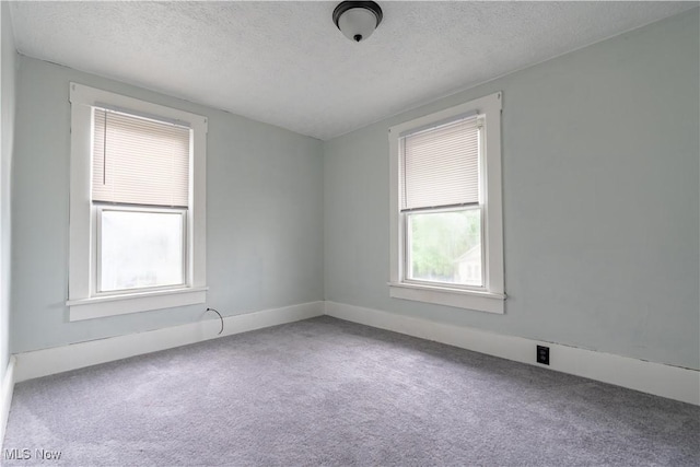 carpeted empty room with a textured ceiling and baseboards