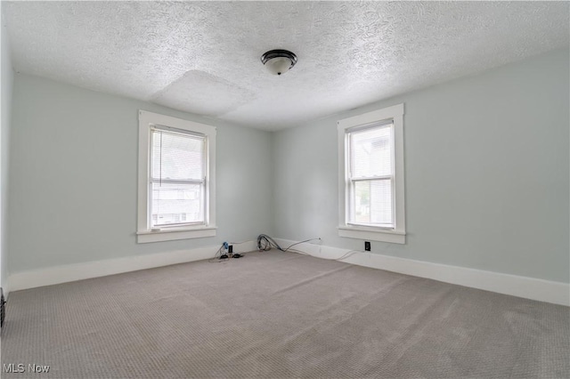 spare room with carpet, a textured ceiling, and baseboards