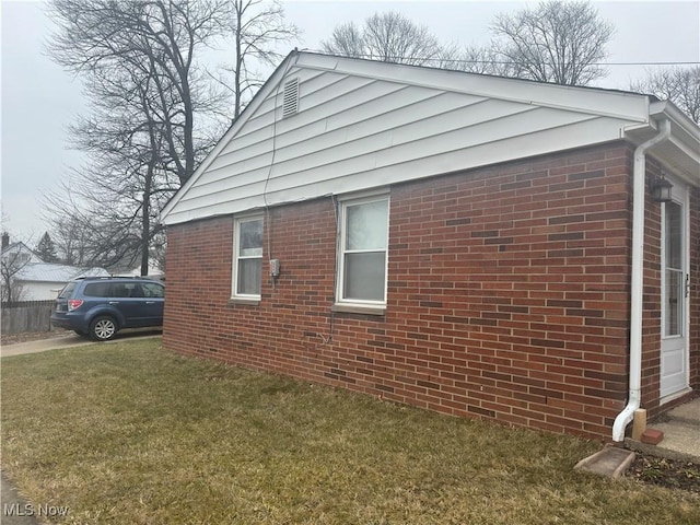 view of side of property featuring a yard and brick siding