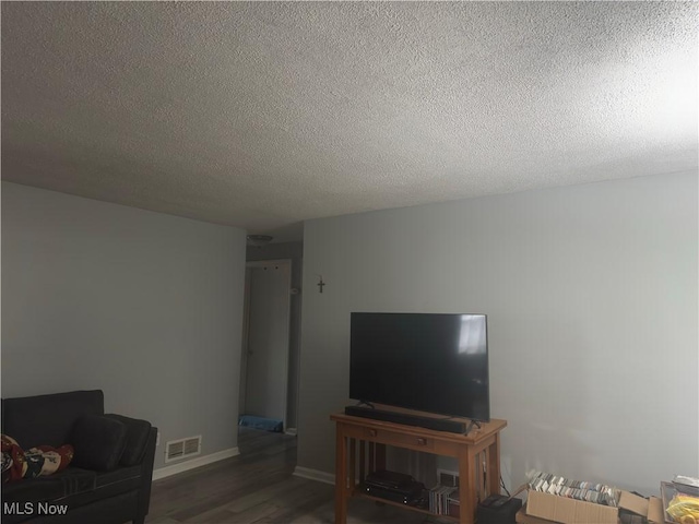 living room with wood finished floors, a textured ceiling, and baseboards