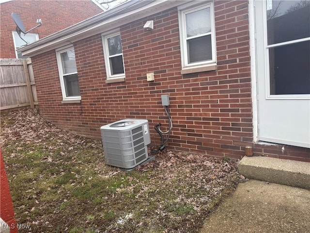 exterior view of central AC, brick siding, fence, and a satellite dish