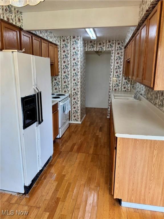 21841 River Oaks Dr Unit B4, Rocky River, OH 44116 - kitchen featuring white appliances, wallpapered walls, a sink, light wood-style floors, and light countertops