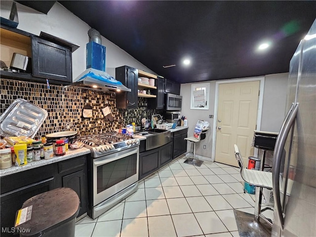 kitchen featuring stainless steel appliances, open shelves, wall chimney range hood, tasteful backsplash, and dark cabinetry