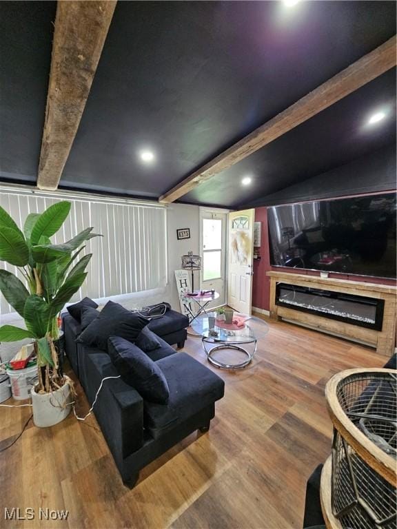 living room with wood finished floors, beamed ceiling, and a glass covered fireplace