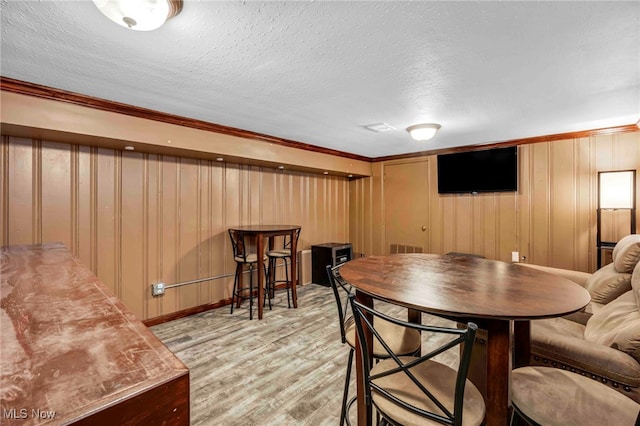 2508 Ashurst Rd, University Heights, OH 44118 - dining room with light wood-type flooring, ornamental molding, a textured ceiling, and baseboards