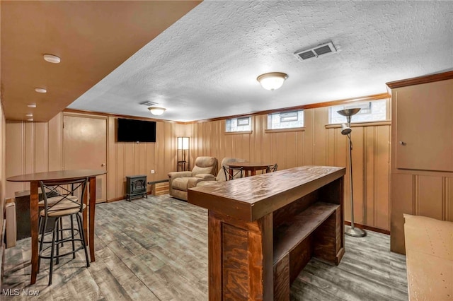 2508 Ashurst Rd, University Heights, OH 44118 - game room with wood finished floors, a wood stove, a textured ceiling, and a decorative wall