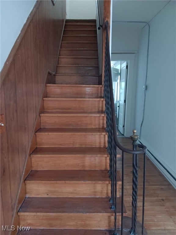 stairs with wood finished floors and wooden walls