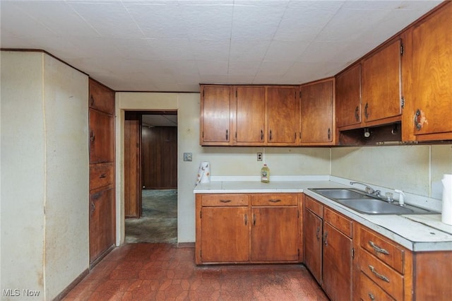 kitchen featuring a sink, brown cabinets, and light countertops