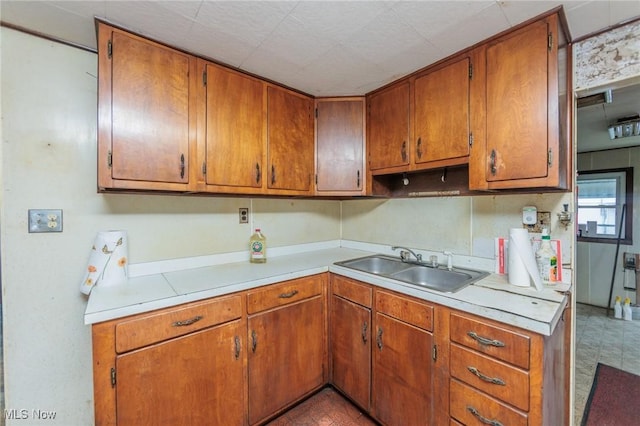 kitchen with a sink, light countertops, and brown cabinets