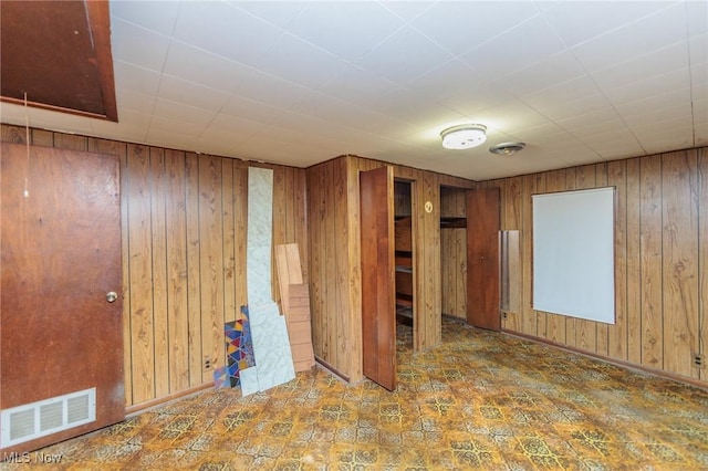 unfurnished room with wooden walls and tile patterned floors