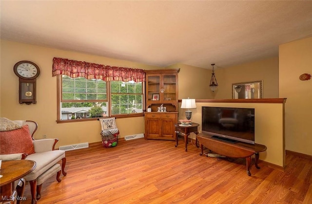 sitting room with light wood-style floors, lofted ceiling, and baseboards