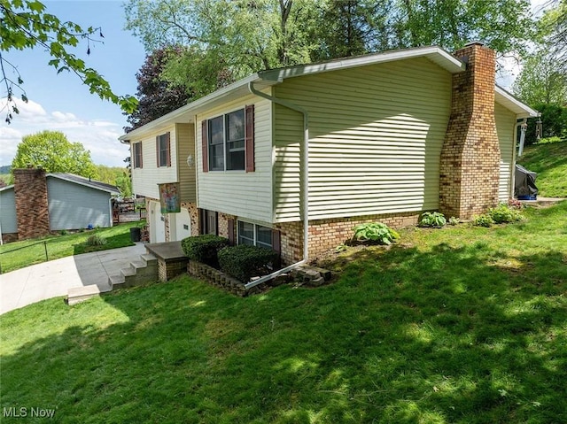view of side of home featuring a chimney, a yard, concrete driveway, and an attached garage