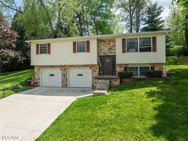 raised ranch with a garage, concrete driveway, brick siding, and a front lawn